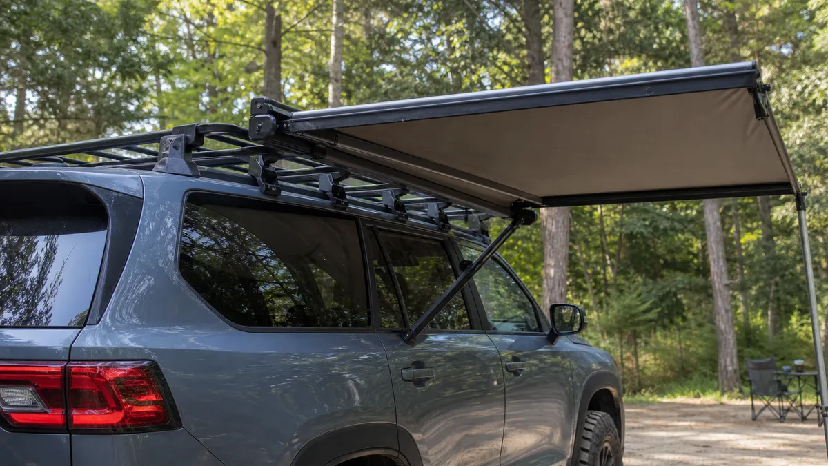 Overland vehicle parked at an outdoor camp stop with roof-mounted travel gear.
