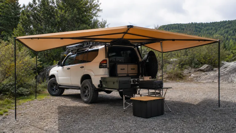 wraparound vehicle awning deployed around the side and rear of an overland vehicle