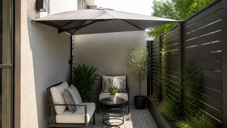 Half umbrella used against a wall on a small patio.